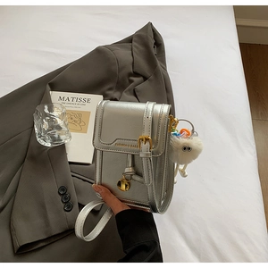 Detail of silver metallic mini crossbody bag with plush charm and fashion logo