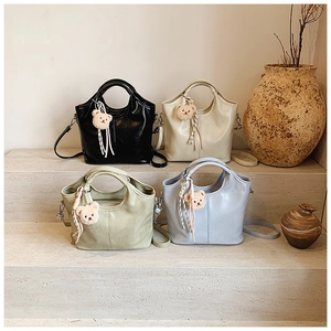 Detail view of four casual bucket bags in black, beige, green, and blue with bear charms