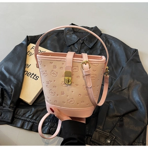 Detail of pink bucket bag featuring embossed bear patterns and a golden metal lock closure