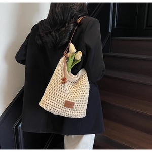 Détail du sac seau en maille ajourée ivoire avec bandoulière en cuir brun et logo de marque