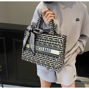 Detail of large canvas tote bag featuring geometric patterns and stylish silk scarf handle