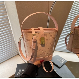 Detail of pink bucket bag featuring embossed bear pattern and golden twist lock