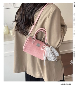 Detail of pink tweed handbag with pearl bow charm worn over a beige blazer