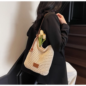 Détail du sac seau en maille ajourée avec sangle en cuir marron et étiquette