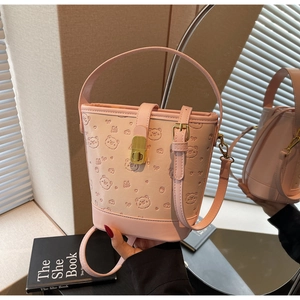 Detailed macro view of pink bucket bag with embossed bear patterns and gold clasp hardware