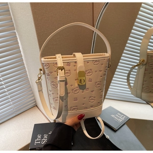 Detail of cream bucket bag with cartoon bear embossing and gold twist lock closure