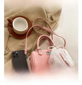 Pink woven Boston bag detail featuring pearl lace bow charm and premium leather handle