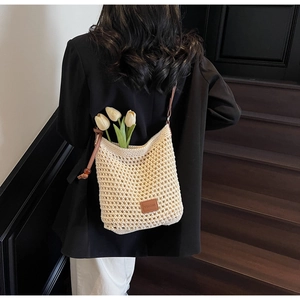 Détail d'un sac seau au crochet avec patch logo en cuir et sangle à perles en bois