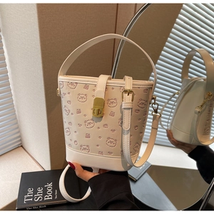 Detailed view of cream bucket bag with embossed bear patterns and gold metal clasp