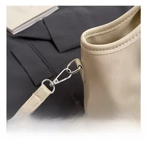 Detail shot of silver metal hook and strap attachment on cream leather bucket bag