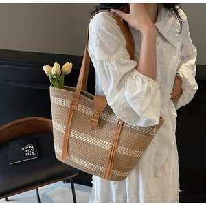 Close-up of retro woven straw tote with brown stripes and premium leather handles