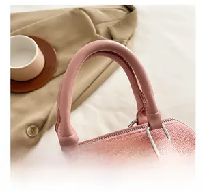 Detailed view of pink woven texture handbag featuring leather handles and silver hardware
