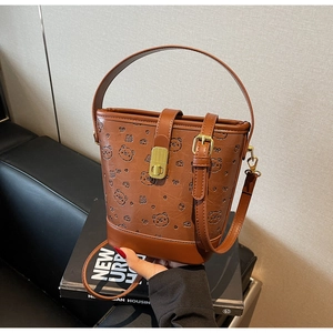 Detail of brown leather bucket bag with embossed bear patterns and metal buckle