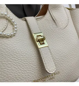 Detail of white lychee leather texture with gold twist lock and pearl handle bucket bag