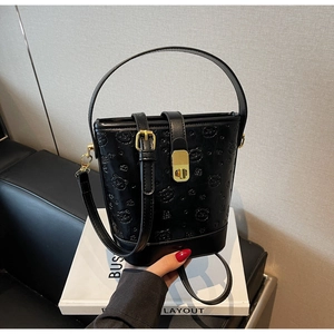 Close-up of black bucket bag featuring teddy bear embossing and gold hardware details