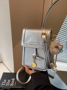 Silver metallic mini crossbody bag with gold text and cute plush monster pendant