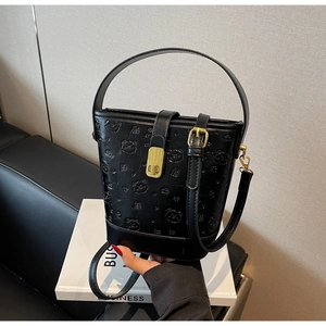 Close-up of black bucket bag with bear embossing and gold metal clasp hardware