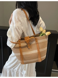 Large straw tote bag with brown and white stripes featuring long tassels and leather handles
