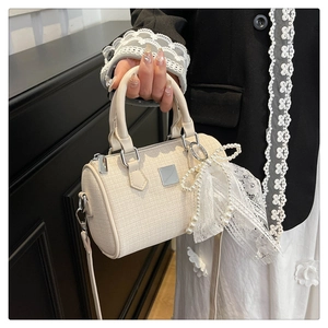 Detail of cream tweed boston bag with lace bow, pearl charms and silver hardware