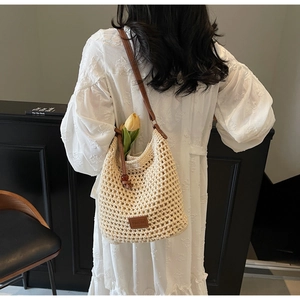 Détail du sac seau en tricot ajouré avec bandoulière en cuir brun et logo de marque