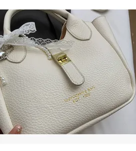 Detail of white lychee leather handbag with gold lock and pearl charm accessories