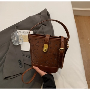 Detail of brown bucket bag with teddy bear embossing and vintage gold metal lock