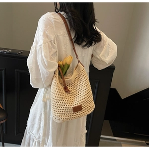 Détail du sac seau en tricot ajouré avec bandoulière en cuir et étiquette latérale
