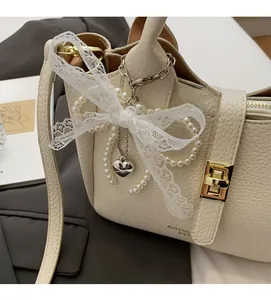 Detail of cream bucket bag with lychee texture featuring lace bow and pearl charms