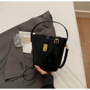 Detail of black embossed leather bucket bag with bear pattern and gold metal clasp