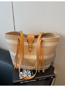 Striped straw tote bag with faux leather straps and tassels on a decorative background