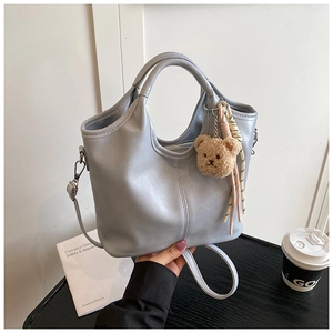 Detail of light blue faux leather bucket bag with teddy bear charm and striped cord