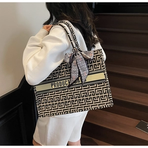 Detail of canvas tote bag with geometric maze pattern and elegant silk scarf on handle