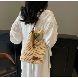 Détail du sac seau en maille ajourée avec bandoulière en cuir porté sur une robe blanche
