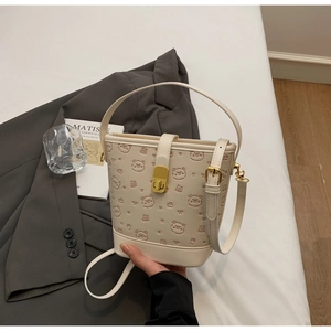 Close-up of cream bucket bag featuring embossed bear patterns and gold metal clasp