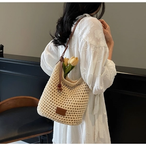 Détail du sac seau en maille ajourée avec étiquette en cuir marron et longue bandoulière