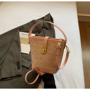 Close-up of pink bucket bag with embossed bear patterns and elegant metal lock detail