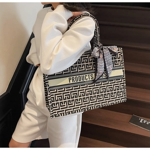 Detail of canvas tote bag featuring geometric square patterns and decorative silk scarf