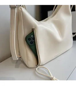 Detail showing creamy PU leather shoulder bag with functional front zip pocket for phone