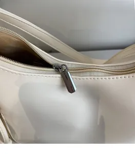 Detail of smooth gunmetal zipper and precise stitching on beige leather tote bag