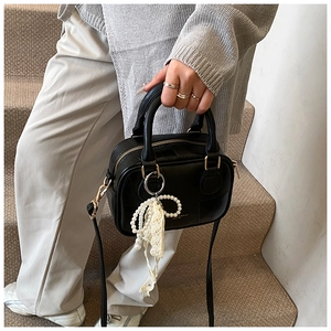 Dettaglio della borsa vintage in pelle nera con chiusura dorata ed elegante ciondolo