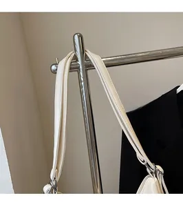 Detail of adjustable shoulder strap on cream faux leather tote with silver buckle