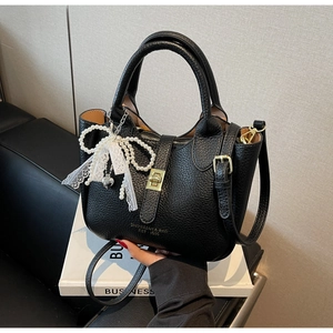Detail of black lychee leather bucket bag with lace bow and pearl pendant