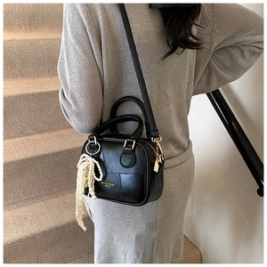 Dettaglio di una mini borsa a tracolla nera con ciondolo di perle e oro
