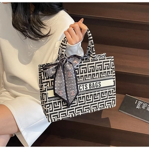 Detail of black and white geometric jacquard canvas tote bag with decorative silk scarf