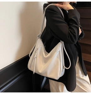 Minimalist light gray tote bag shown on model in a modern urban indoor setting