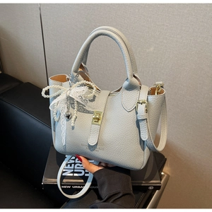 Detailed close-up of blue lychee leather handbag with pearl bow and gold heart charm