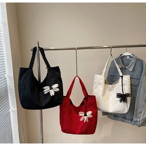 Detailed view of canvas tote bags in black red and white with daisy charm hanging