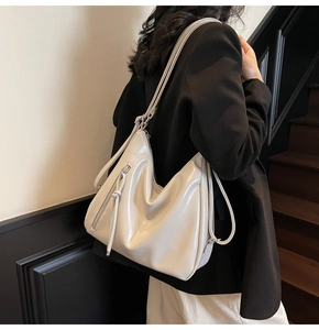 Detail of minimalist cream pleated tote bag with glossy leather texture and side zipper
