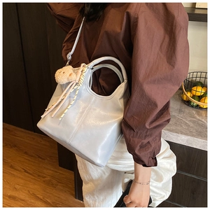 Detail of light blue bucket bag featuring smooth leather texture and cute bear charm