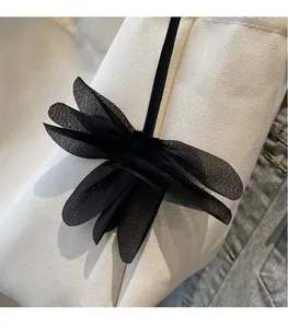 Detail of multi-layered black chiffon bow hair accessory on denim and canvas background